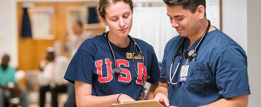 Female and male looking at clipboard with stethoscopes around their necks.