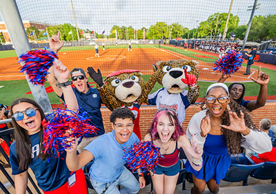 Group of students cheering at baseball game with Southpaw and Ms. Pawla.