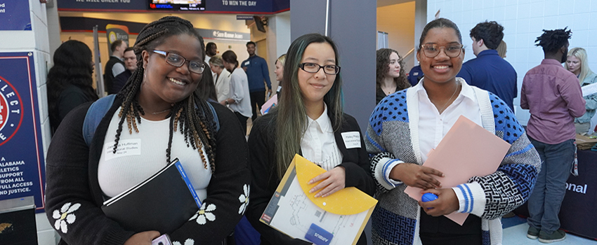 Three students holding packages at the career fair.