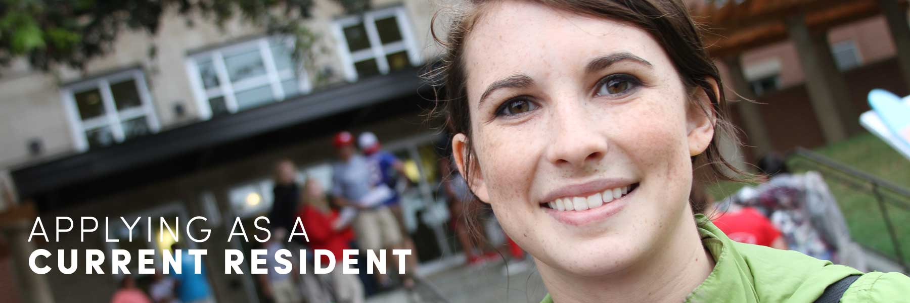 Student smiling in front of dorms